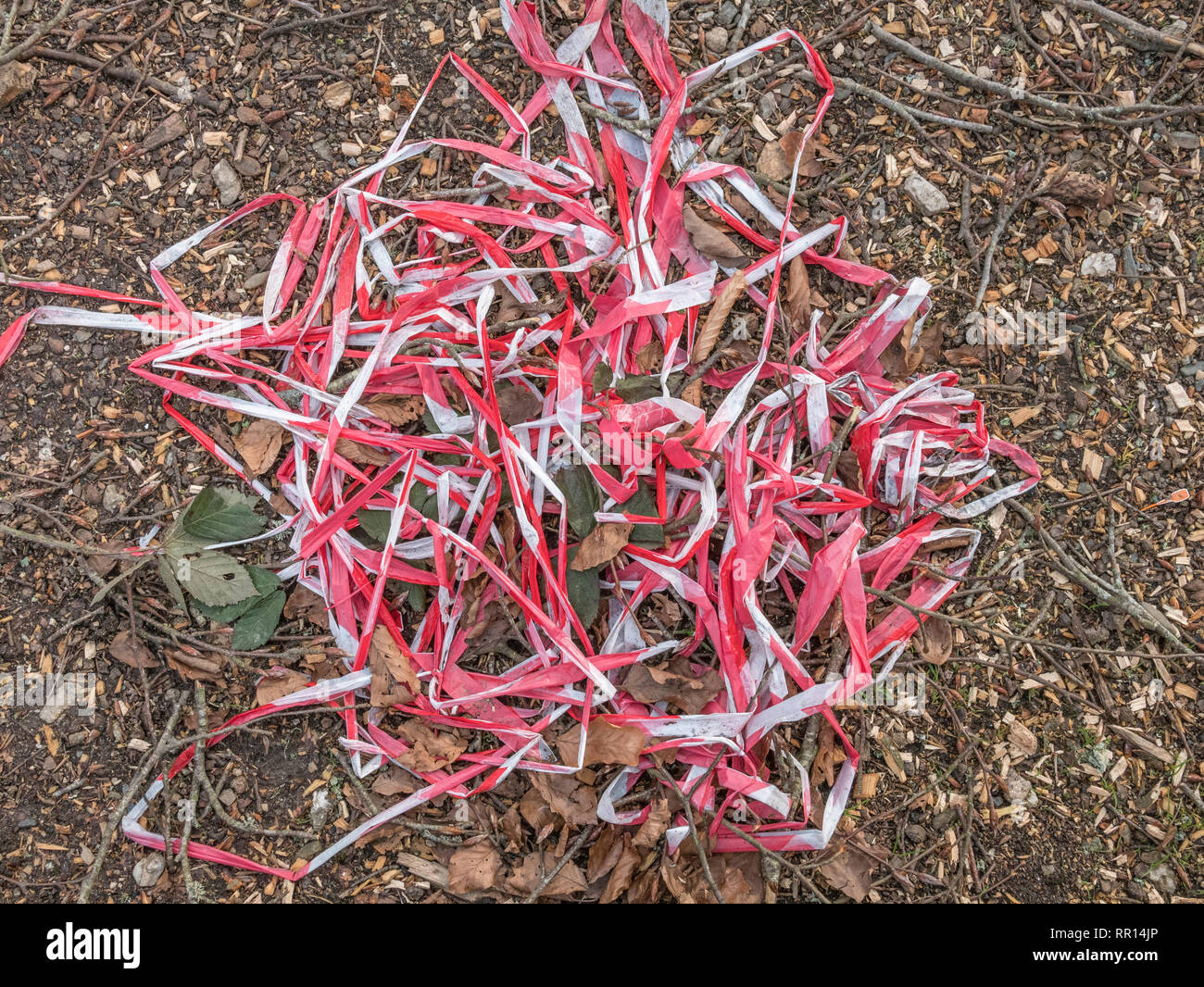 Pile of abandoned red and white barrier warning tape left on the ground