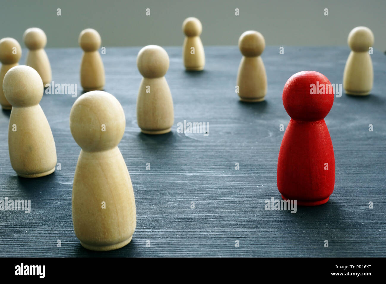 Crowd of figurines with red one. Uniqueness and Individuality. Stock Photo