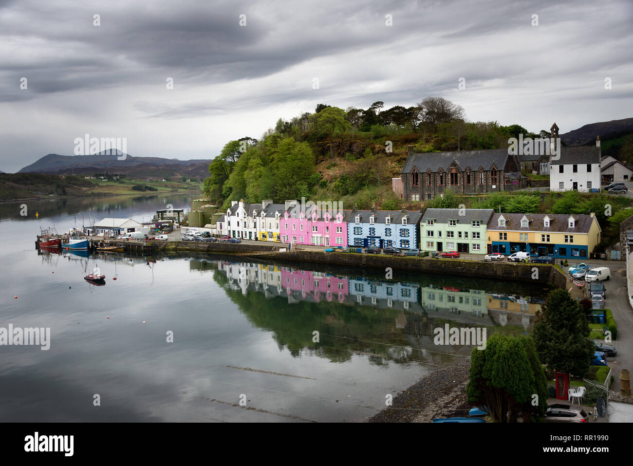 Colorful rainbow houses with reflection in the water of the harbor of Portree on an overcast day on the Isle of Skye, Inner Hebrides in Scotland, UK. Stock Photo