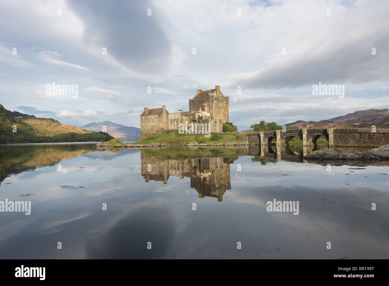 Historic Eilean Donan castle in the early morning light with great clouds in the sky and with reflection in the water near Skye in Scotland, UK. Stock Photo