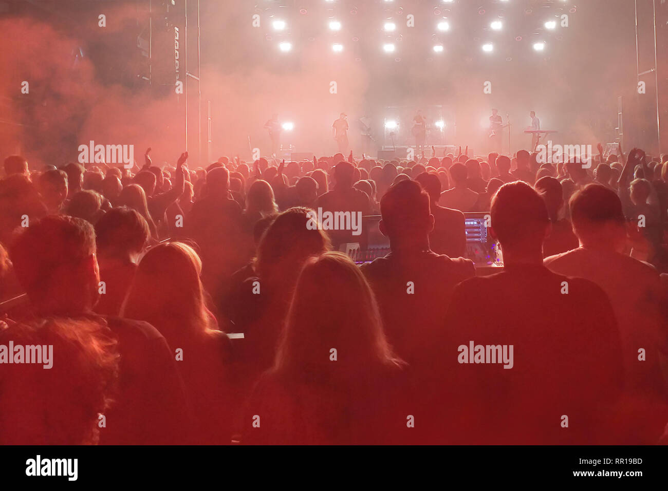 Crowd of people with raised hands on the dance floor in night club Stock Photo