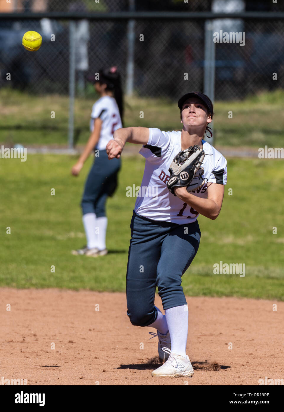 Softball player in white uniform watching thrown ball fly during game between Foothill Technology High School and Pioneer Valley on February 23, 2019. Stock Photo