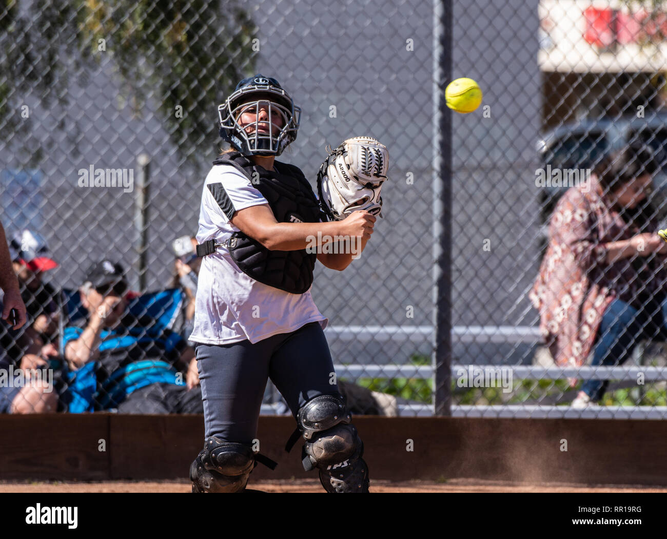 Softball player in white uniform catcher throwing a pick up play to first base during game