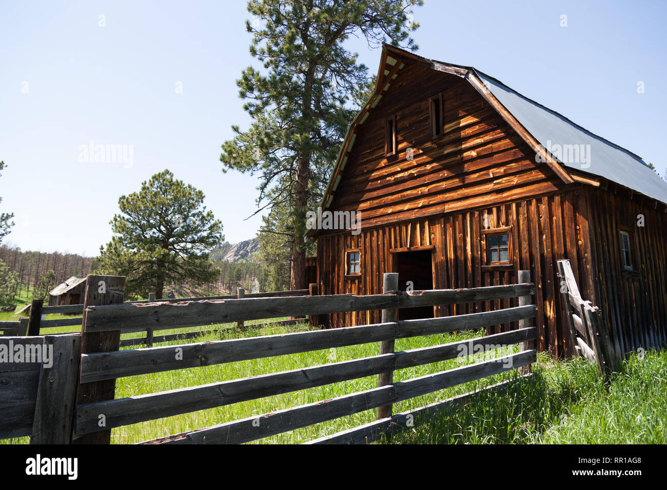 An old wooden barn with a fenced in corral and tall green grass on an ...