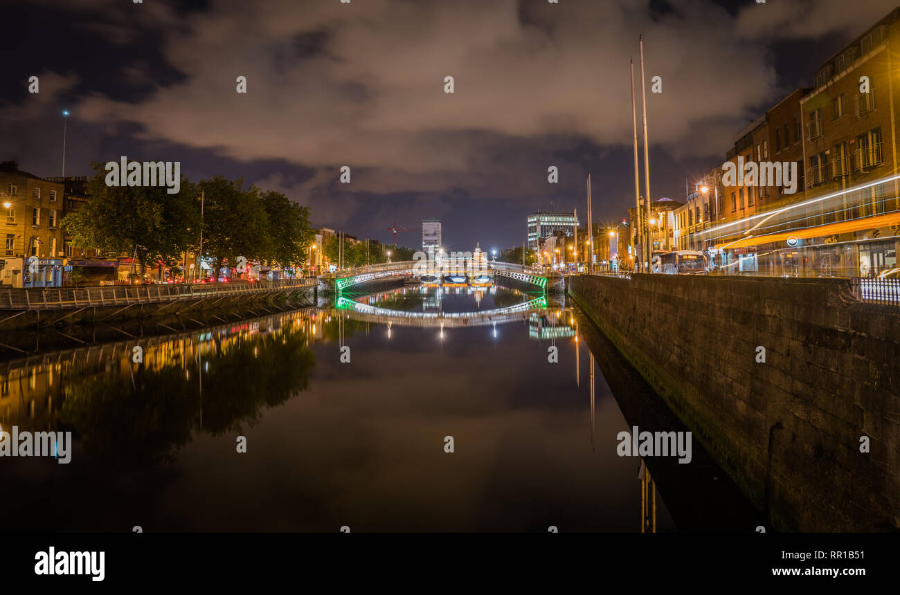 Hapenny or Liffey Bridge in Dublin, Ireland on a cloudy night with neon city lights Stock Photo