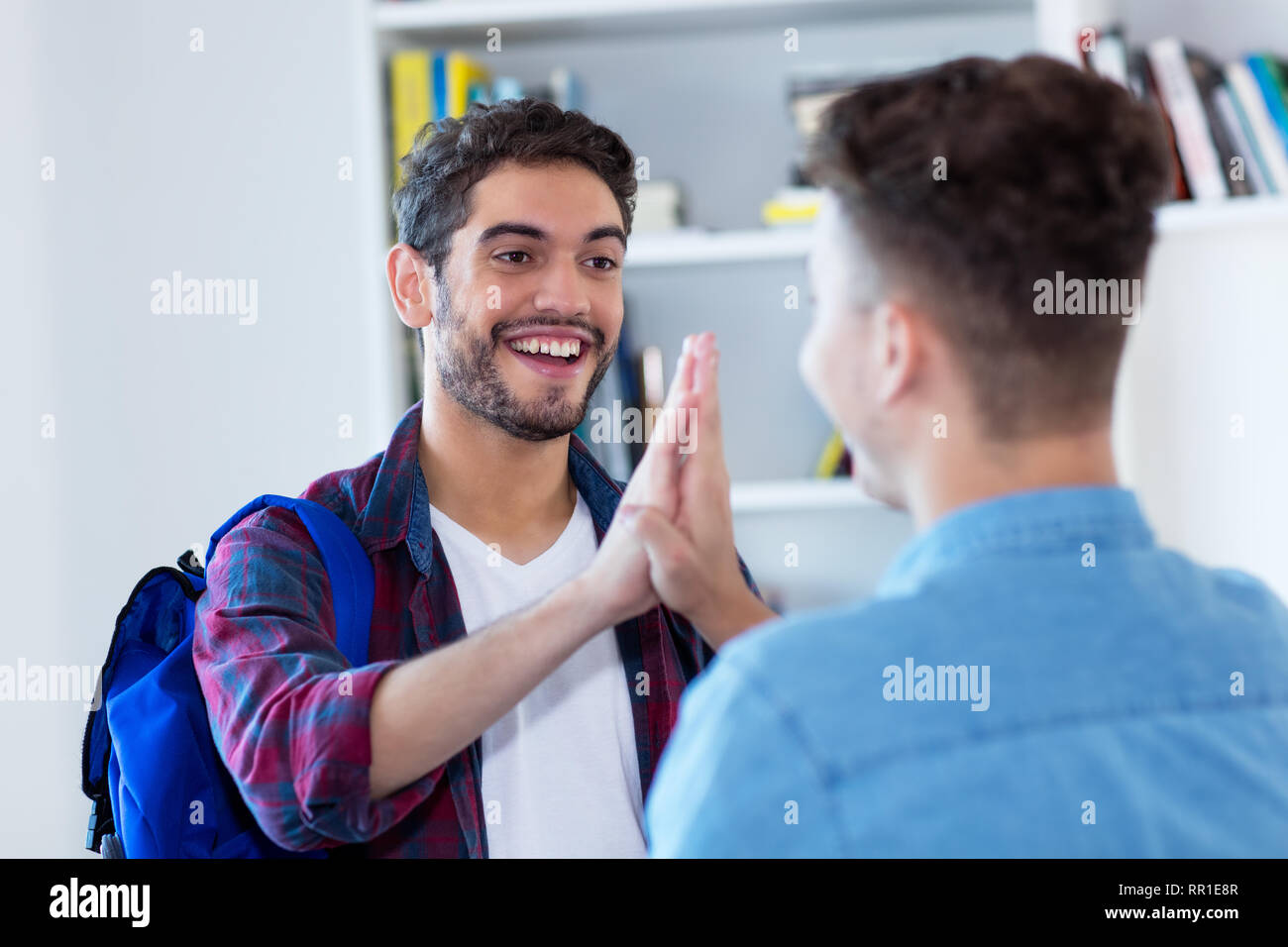 Two male students giving high five at library of school Stock Photo