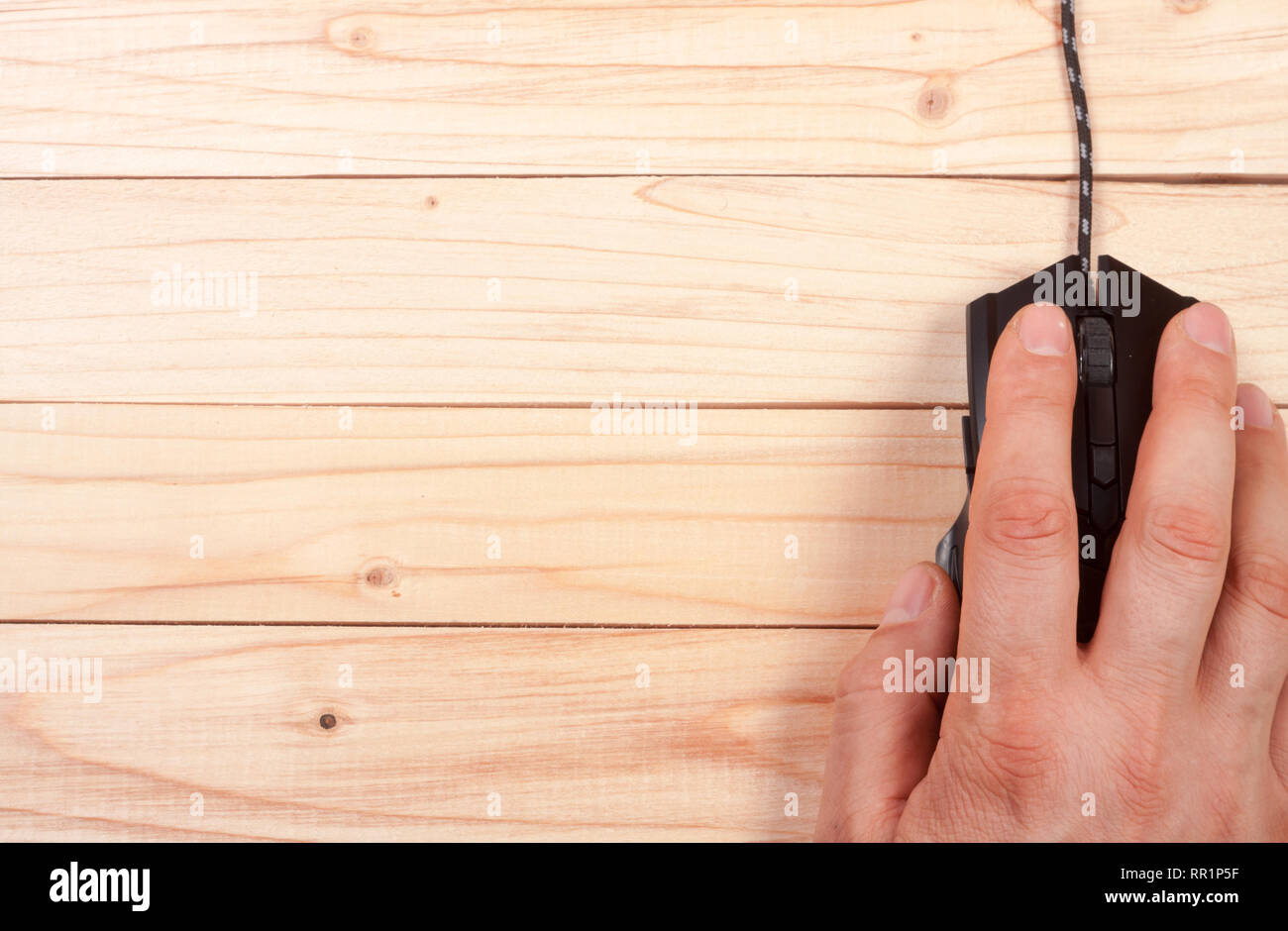 black computer mouse with a hand on a light wooden background with copy ...