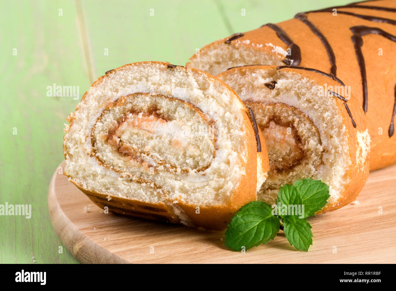 Biscuit swiss roll close-up on green wooden background Stock Photo