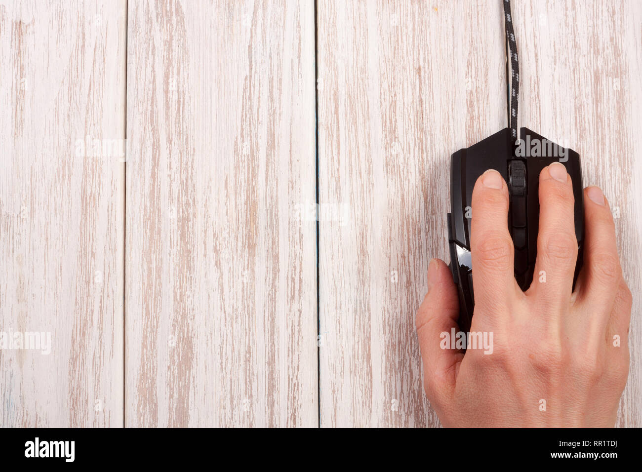 black computer mouse with a hand on a white wooden background with copy ...