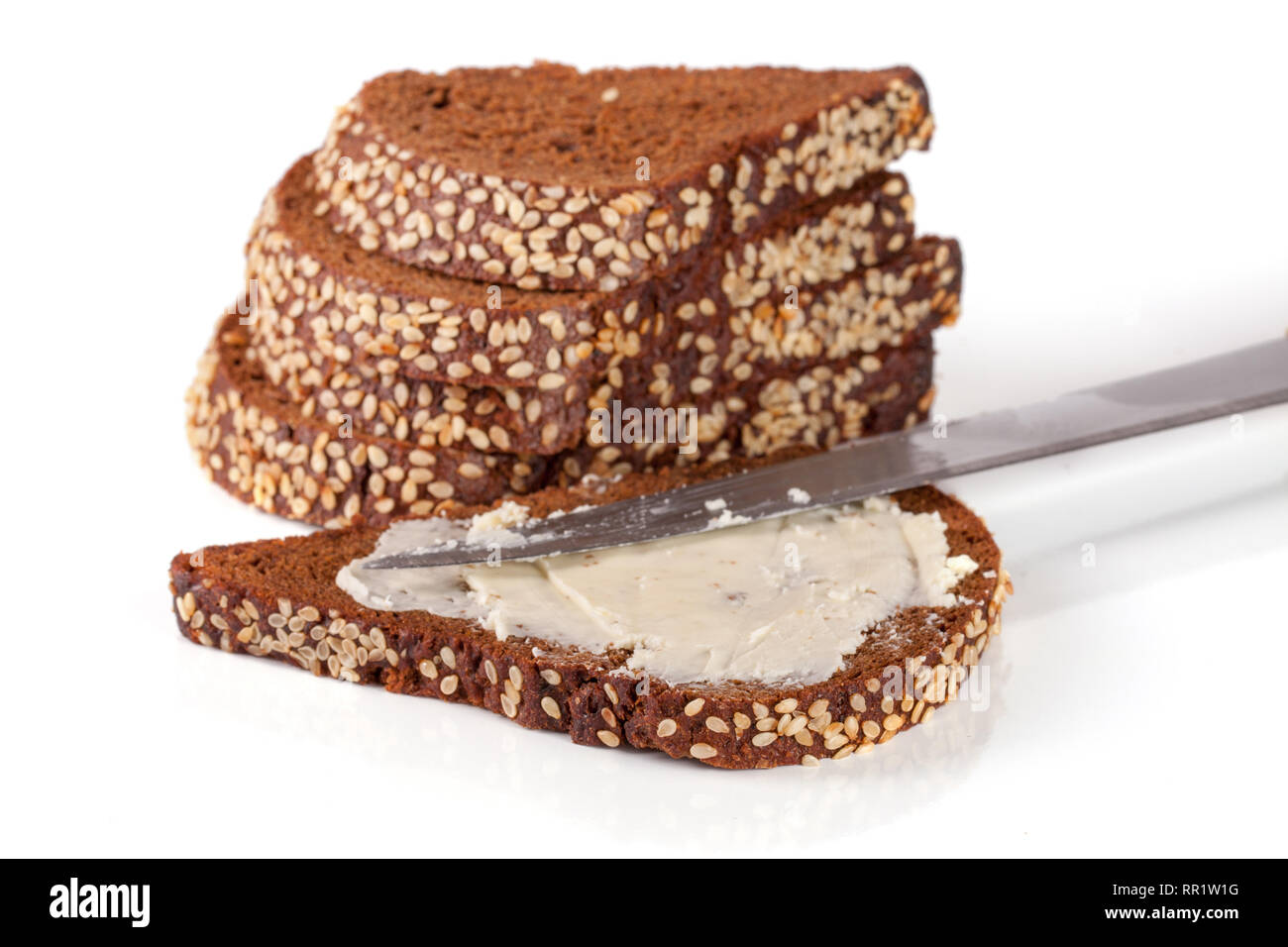 slices of black bread with sesame seeds and butter isolated on white ...