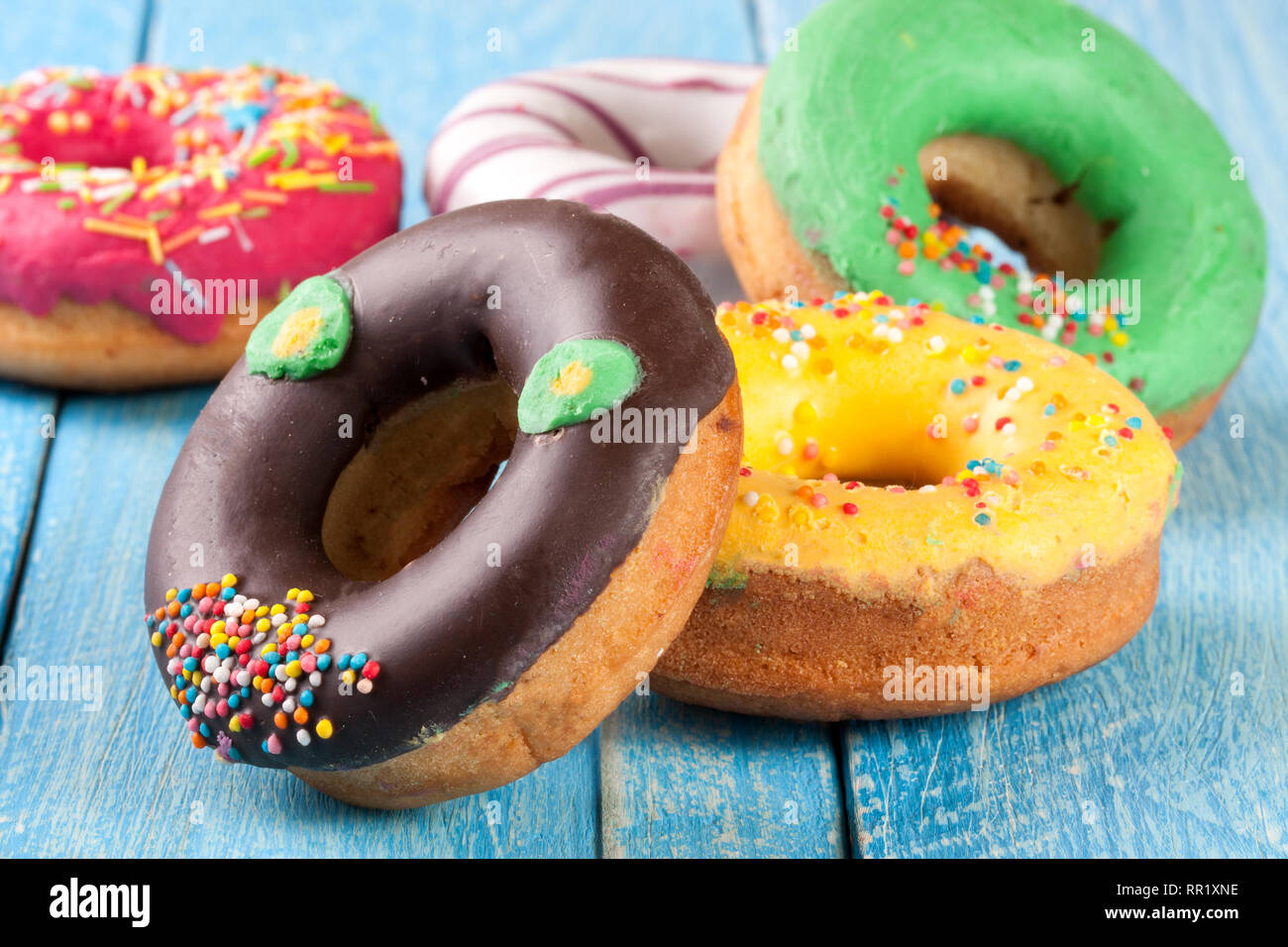 pile of glazed donuts on a blue wooden background Stock Photo - Alamy
