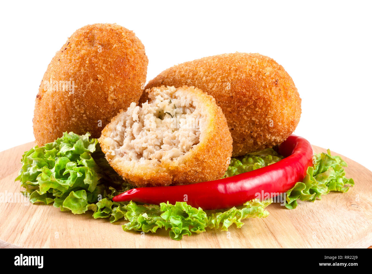 three fried breaded cutlet with lettuce on a cutting board isolated ...