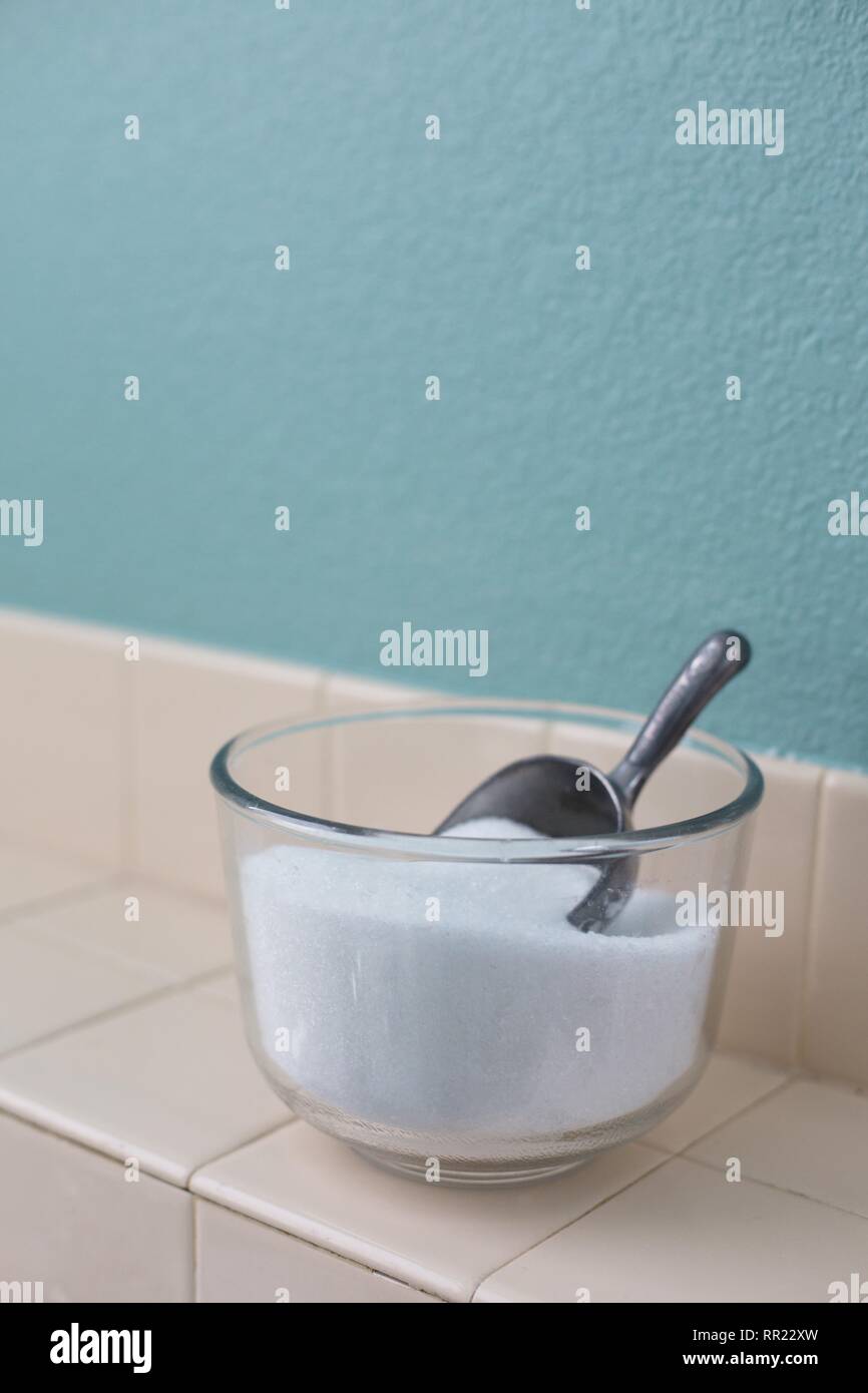 A bowl of epsom salts with a scoop, next to a bathtub Stock Photo Alamy