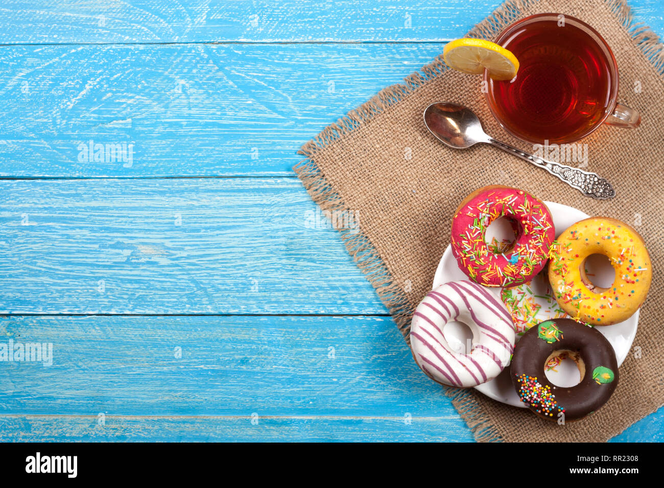 glazed donuts with a cup of tea on a blue wooden background with copy ...