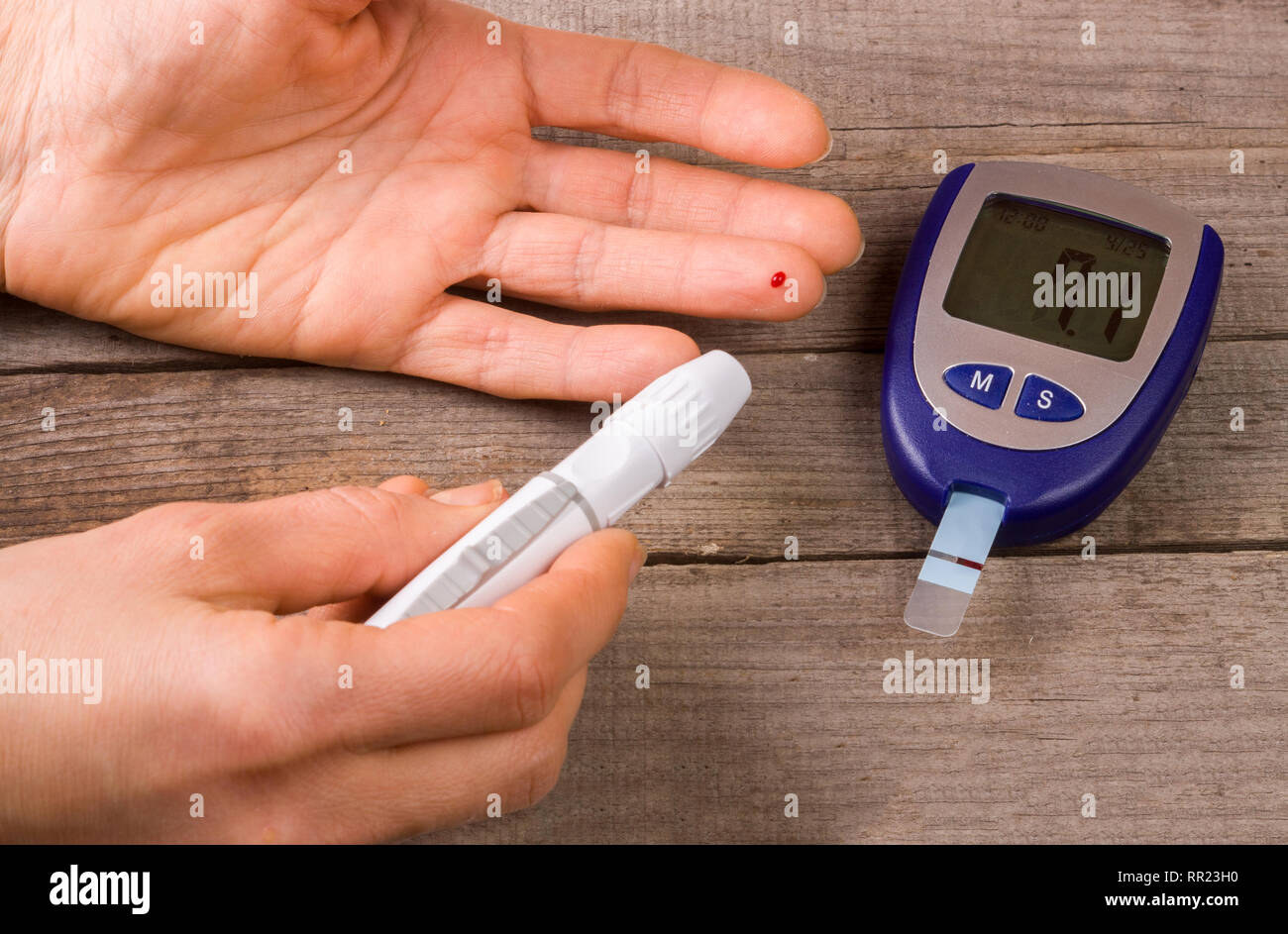 https://c8.alamy.com/comp/RR23H0/blood-glucose-meter-with-a-hand-on-an-old-wooden-background-RR23H0.jpg