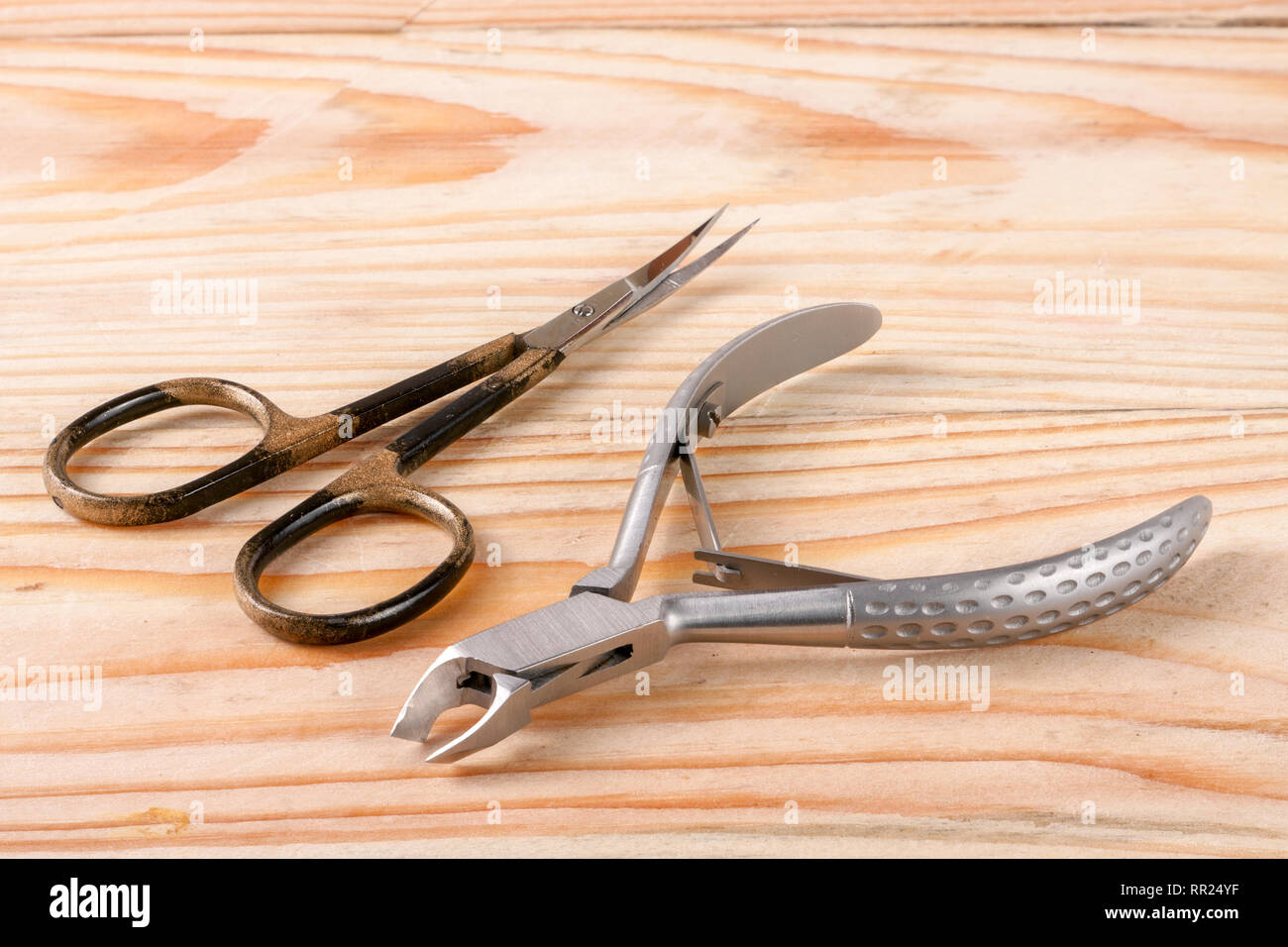 nail scissors and clippers to remove the cuticle care products on a light wooden background