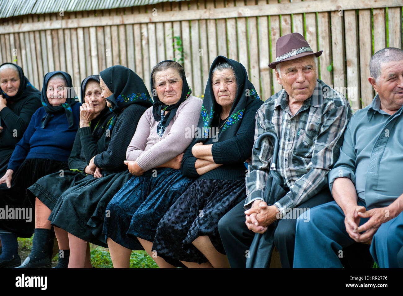 Villagers sitting on a street waiting for the Pentecost procession, in the village of Poienile Izei, famous for its wooden church, in the Maramure? re Stock Photo