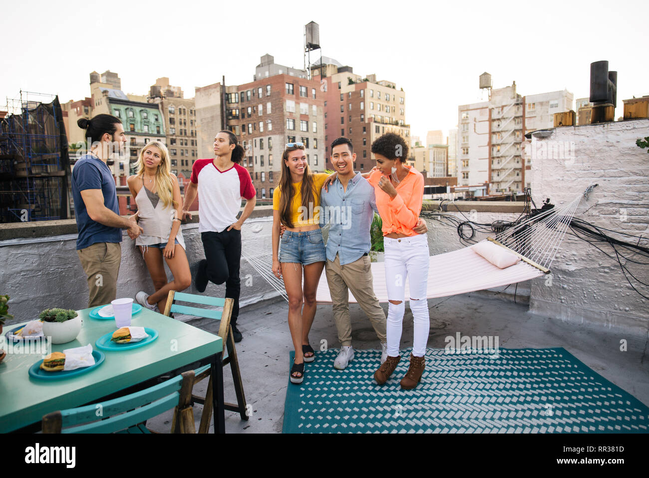 Young happy people having a barbecue dinner on a rooftop in New York Group of friends having
