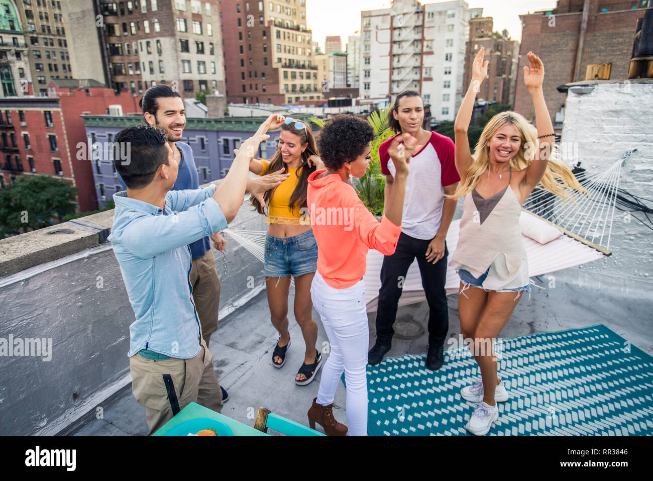 Young happy people having a barbecue dinner on a rooftop in New York