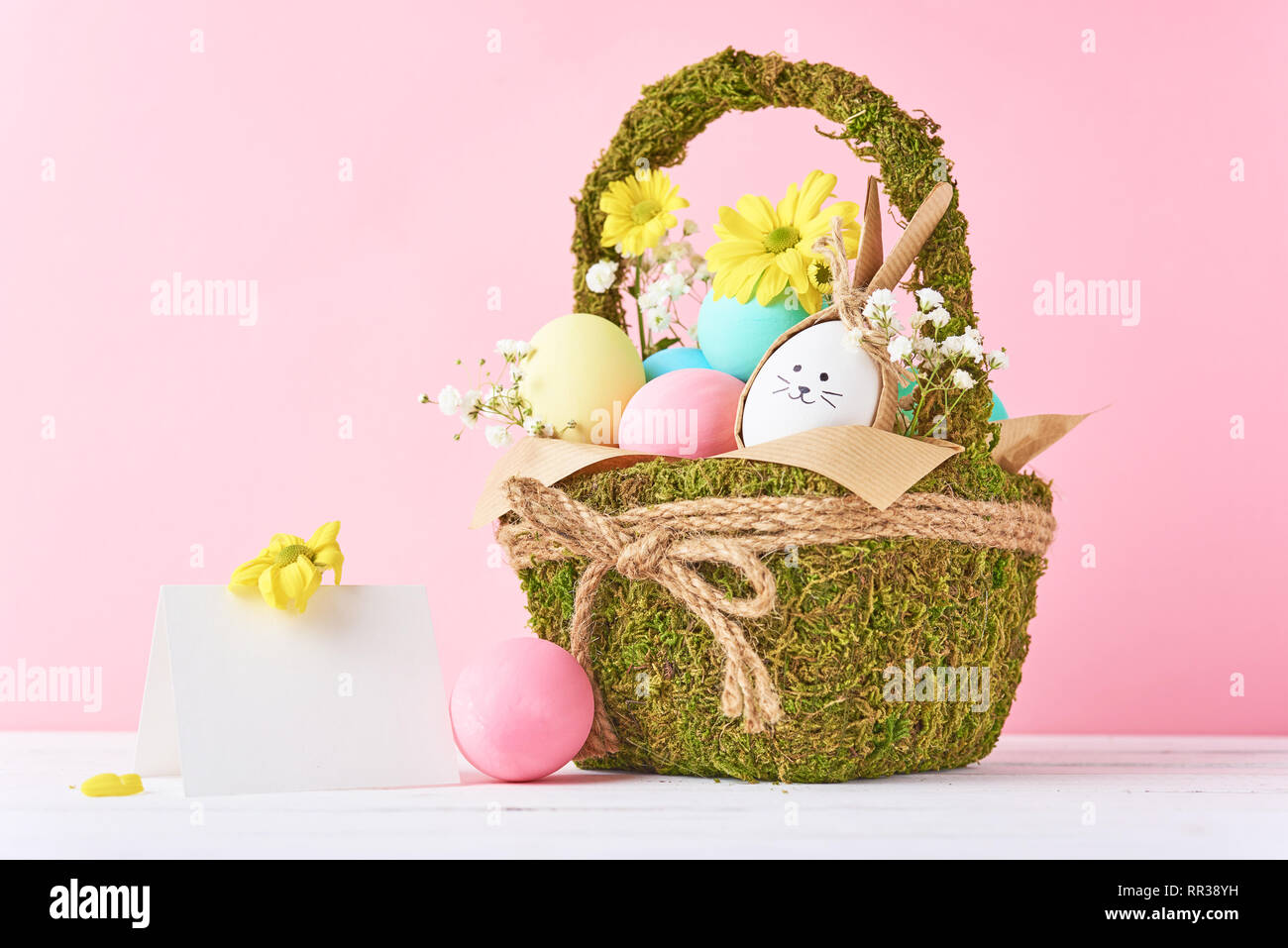 Easter concept. Easter eggs in decorative basket with flowers on pink ...