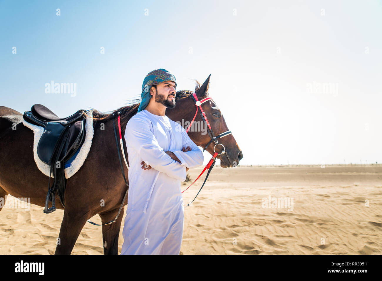 Middle eastern handsome man with typical emirates dress riding a arabic