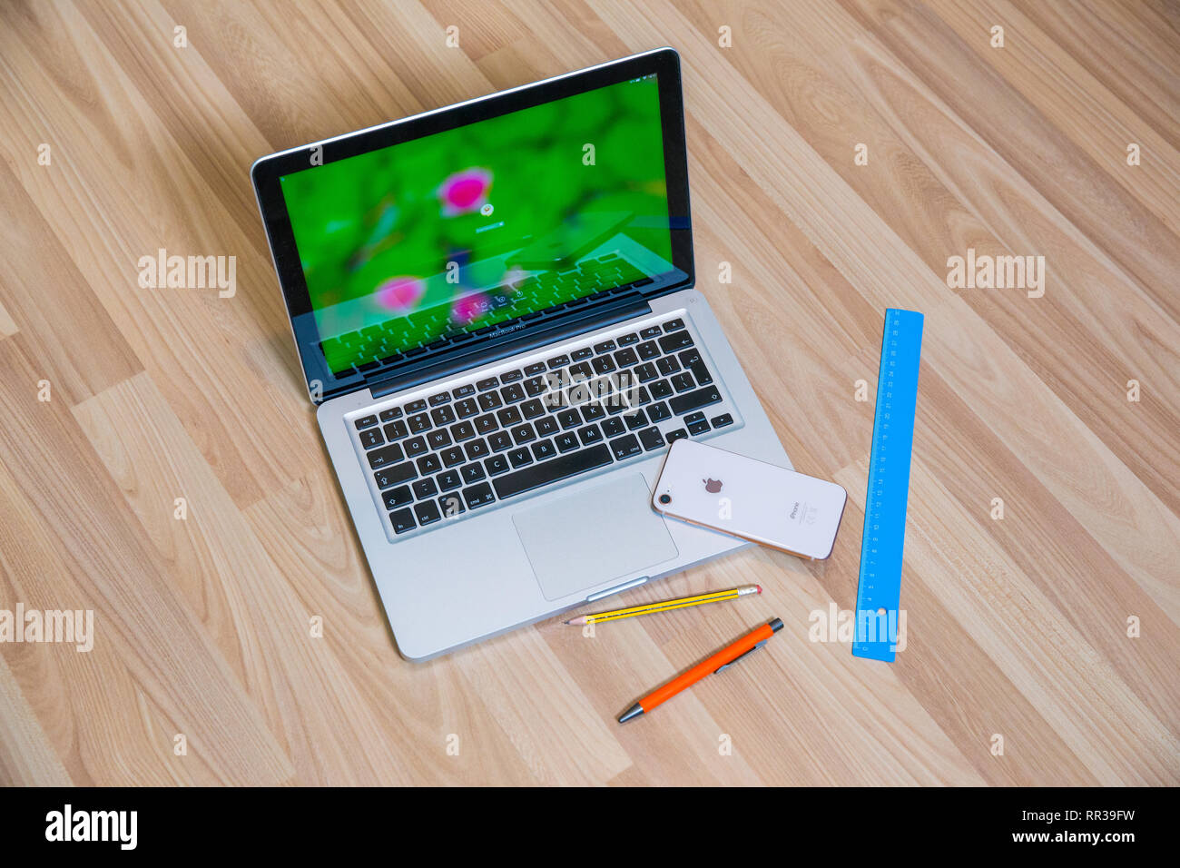 City Riga, Latvia. Apple gold phone and Mac book pro in living room. Old wooden texture and pen. Urban home design 2019. Stock Photo