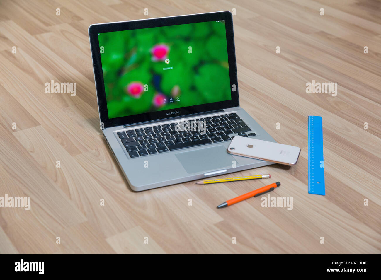 City Riga, Latvia. Apple gold phone and Mac book pro in living room. Old wooden texture and pen. Urban home design 2019. Stock Photo