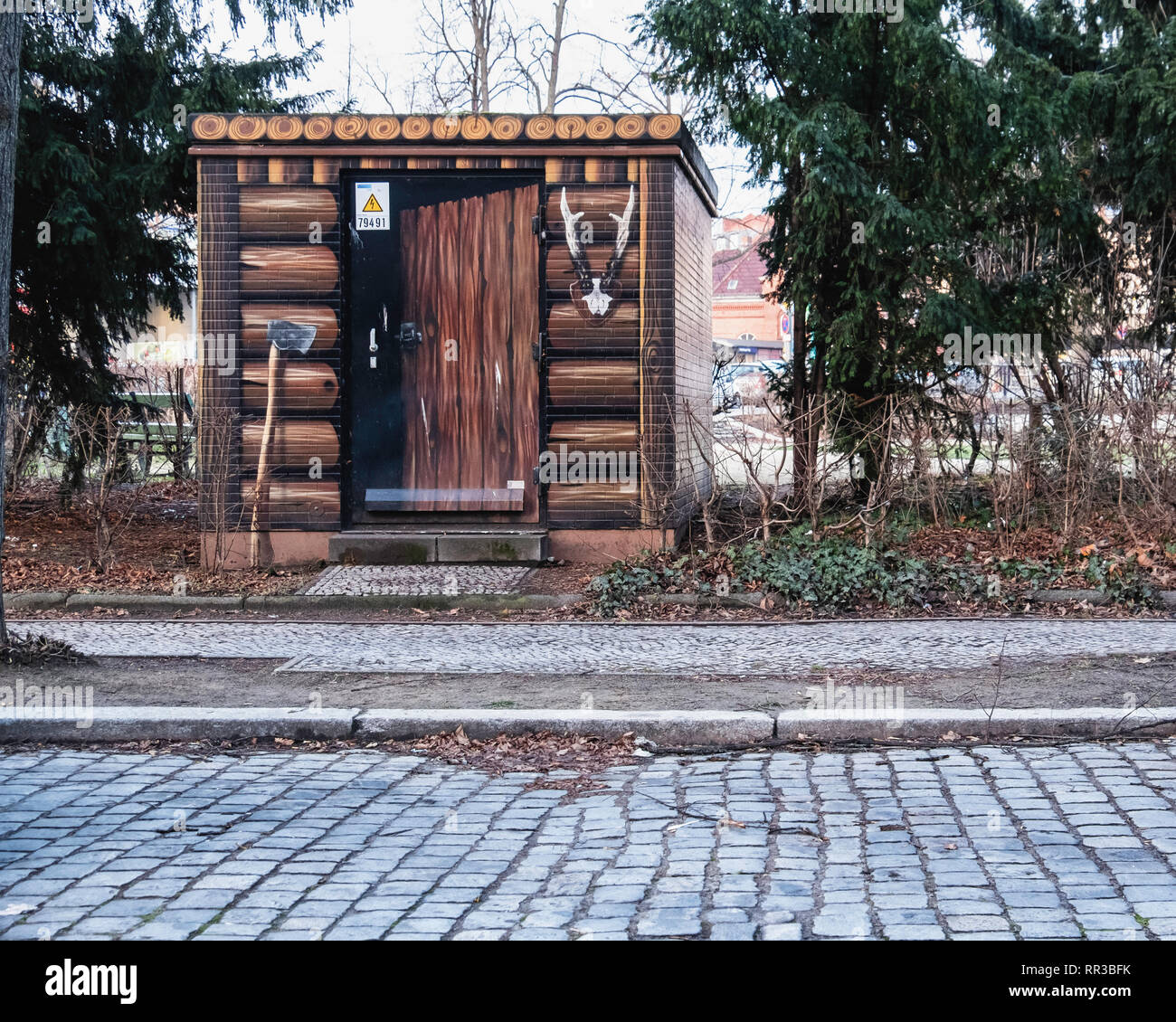 Heidelberger Platz, Wilmersdorf-Berlin.Utility box disguised as forester's shed - Paintwork of logs, ax and deer antlters Stock Photo