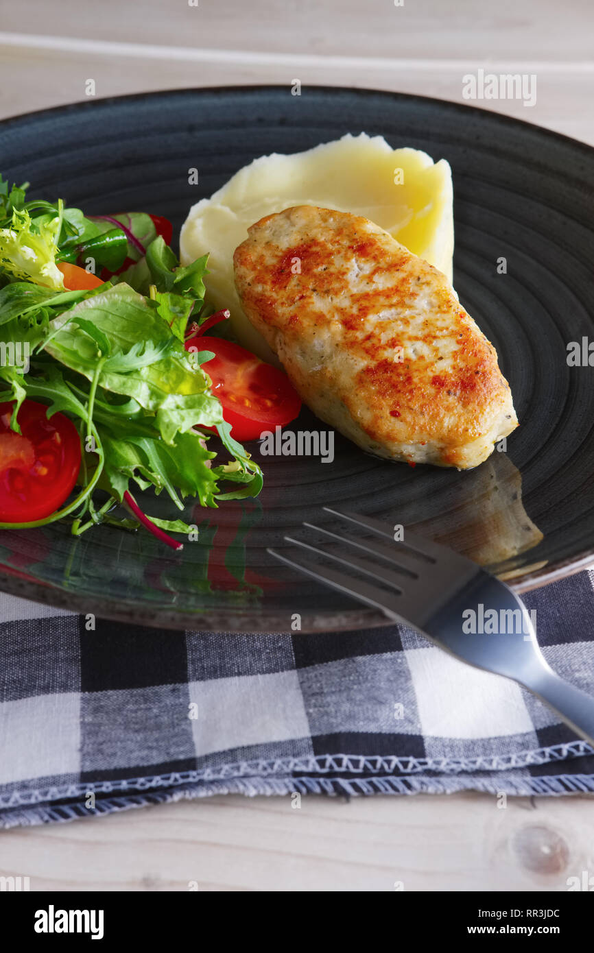 Fried chicken patty with mashed potato and fresh arugula, tomato and