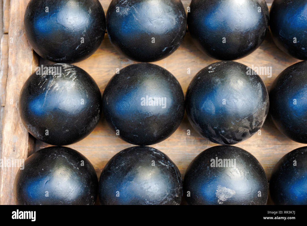 Three rows of vintage iron cannon balls of black colors. History of military technology Stock Photo