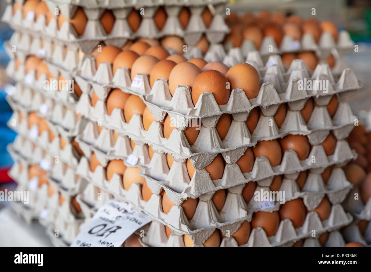 Chicken eggs in the market. Carton packages with brown eggs stacked background, texture. Closeup view Stock Photo
