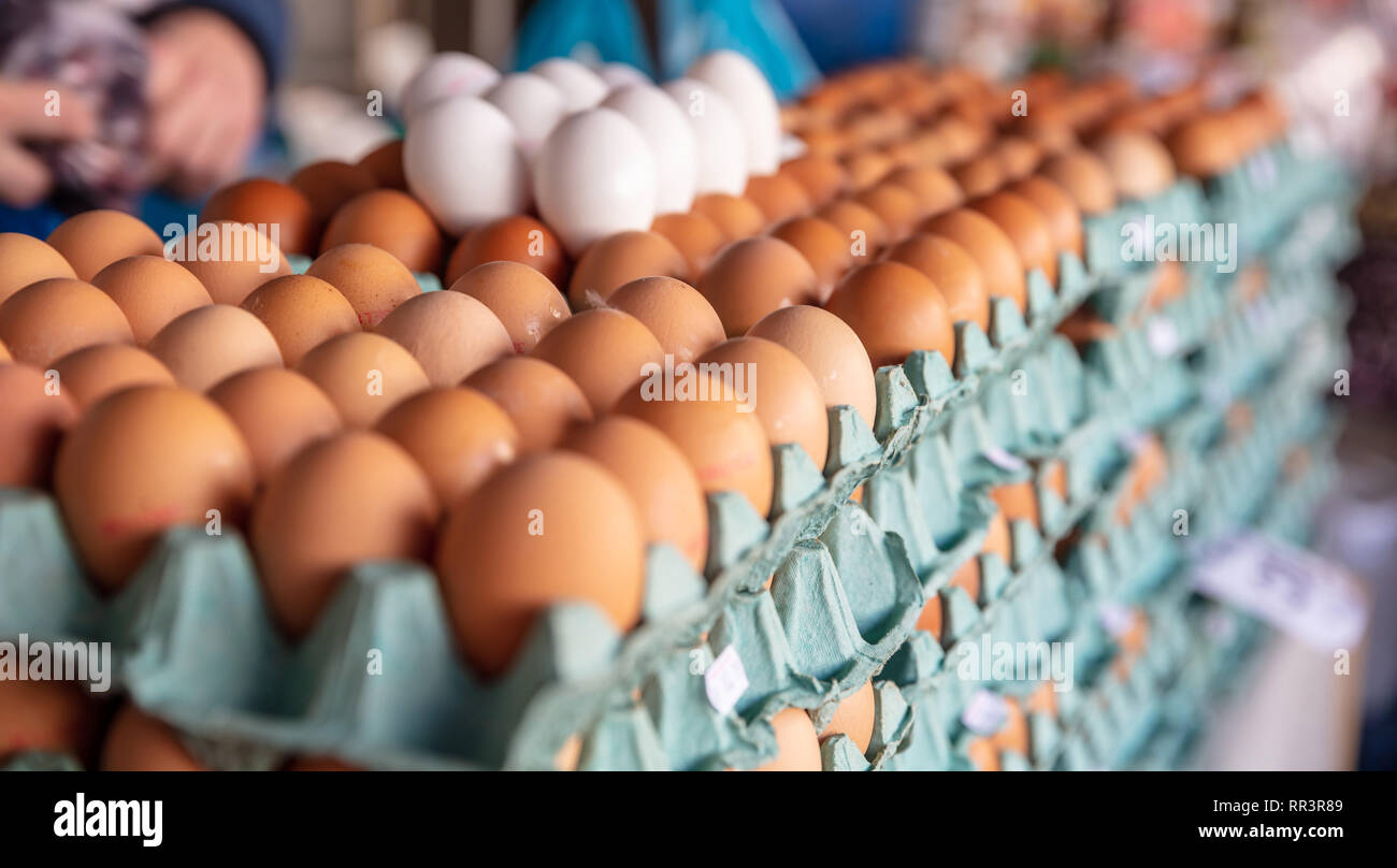 Chicken eggs in the market. Carton packages with eggs stacked background, texture. Closeup view Stock Photo