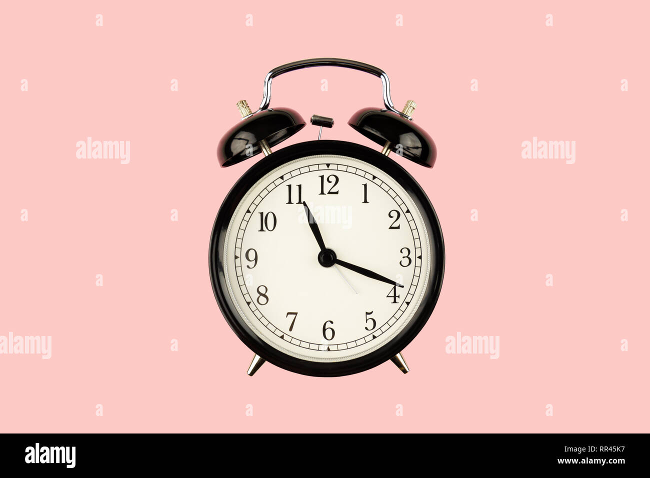 Black retro alarm clock on pink background closeup Stock Photo