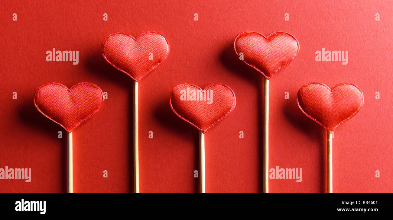 Red textile hearts on wooden sticks closeup. Valentines day background, creative texture and love concept Stock Photo