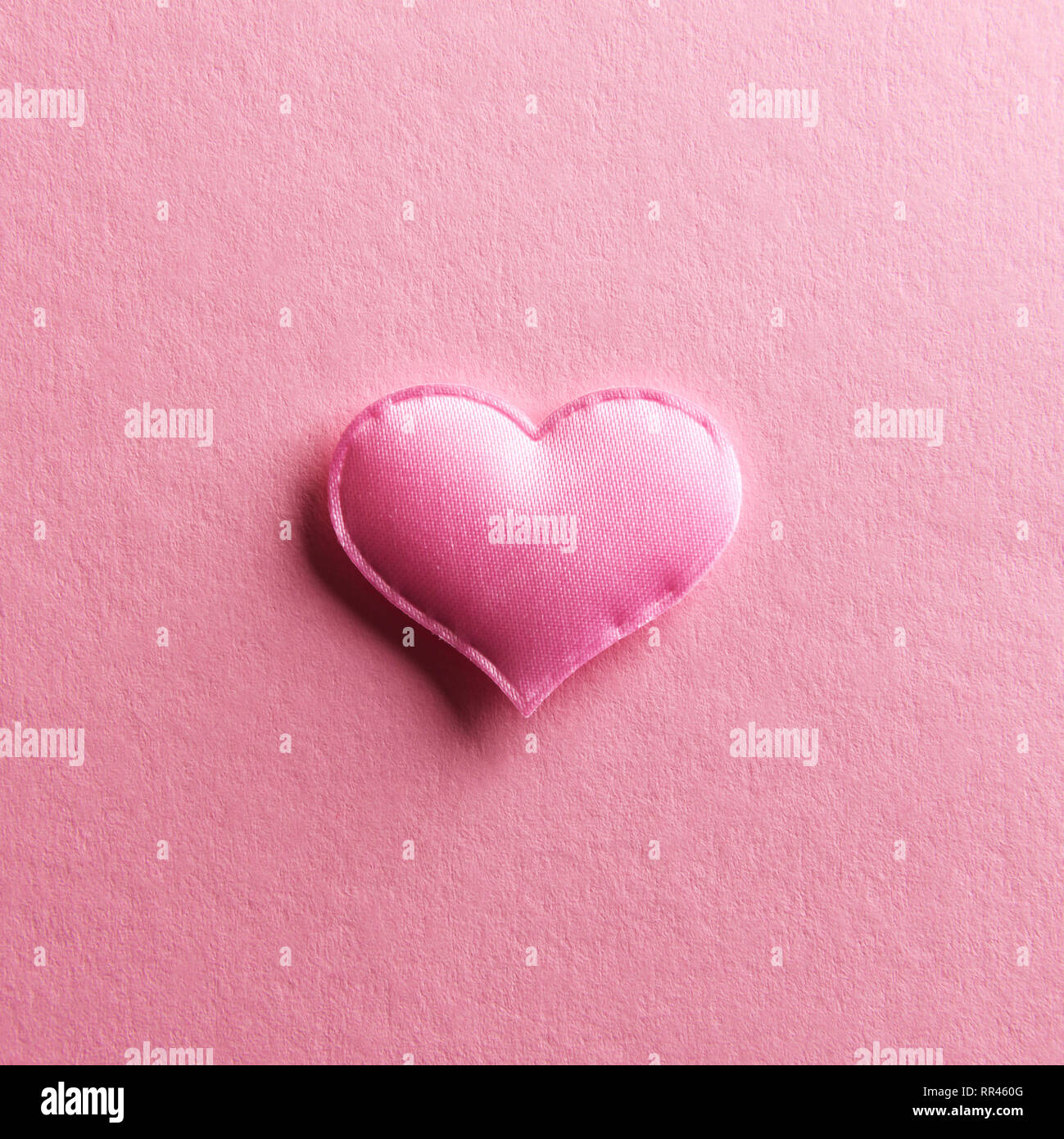 Pink textile heart on pink background. Valentines day texture and love concept Stock Photo