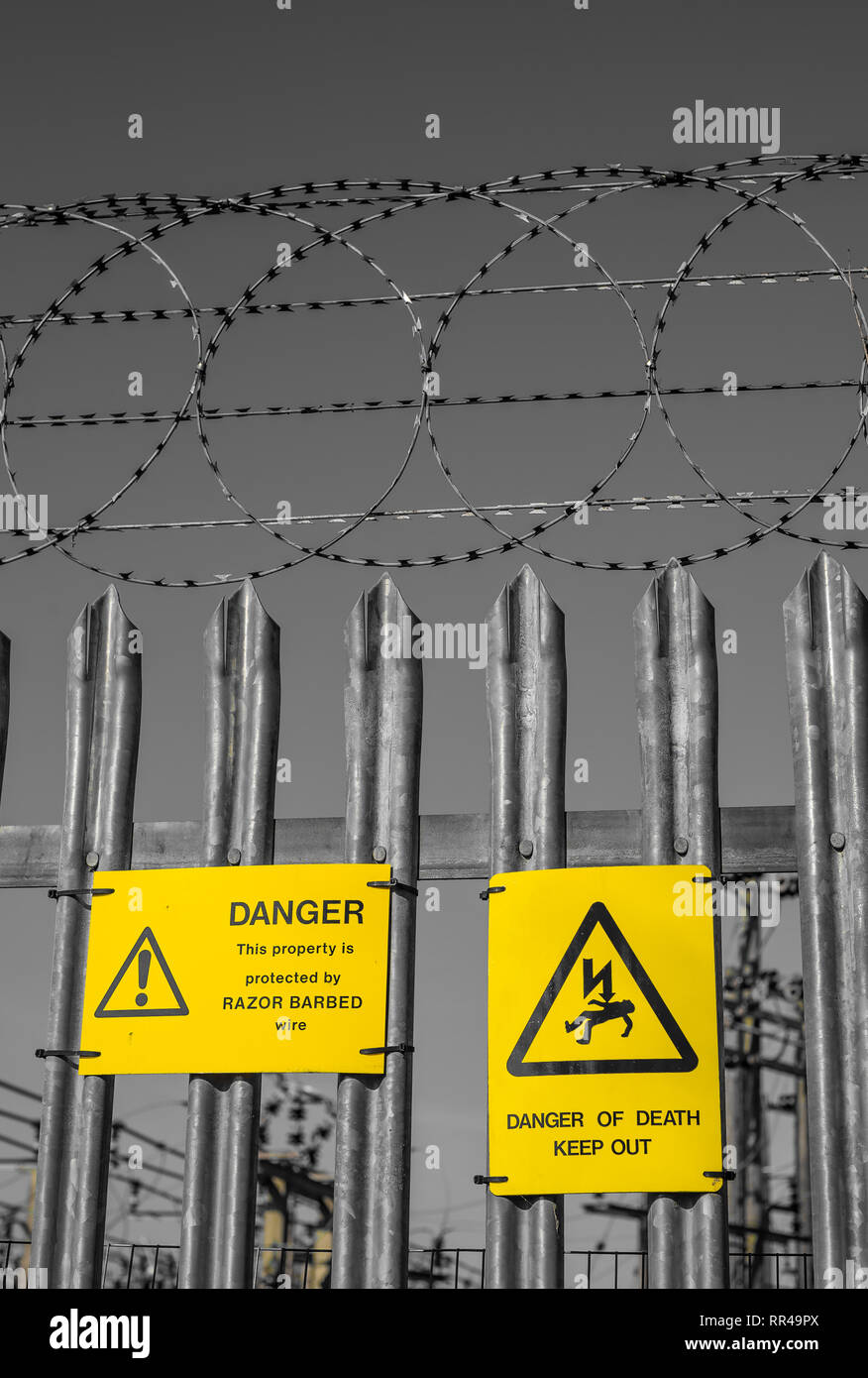 Warning signs and razor wire surround a electricity substation in Ducklington Oxfordshire UK Stock Photo