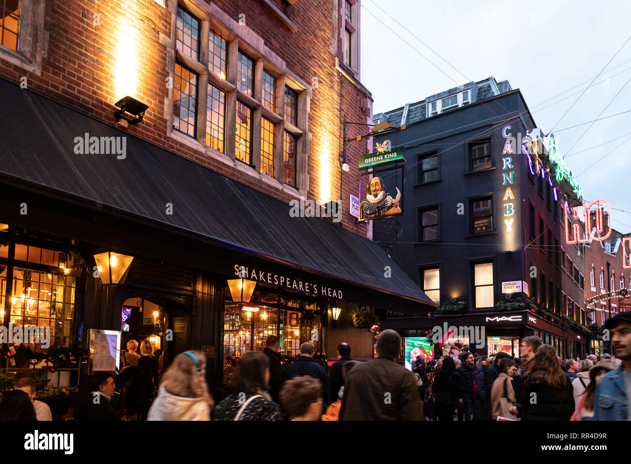 London, United Kingdom - December 29 2018:   Shoppers and Sightseers throng past the Shakespeare Head pub and MAC make up store on Carnaby Street Stock Photo