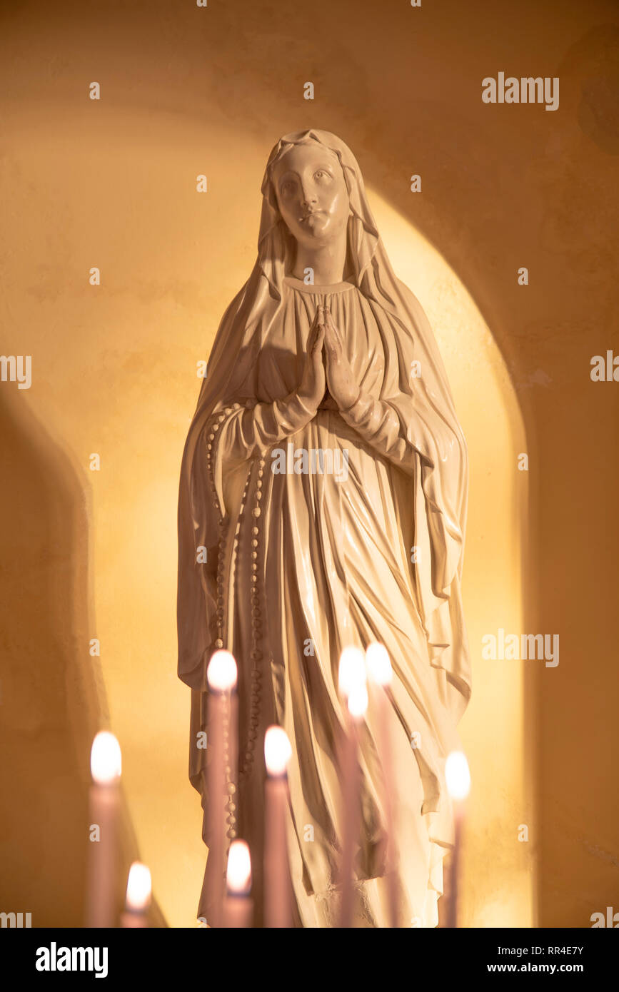 Statue of the Virgin Mary with candles in the foreground Stock Photo