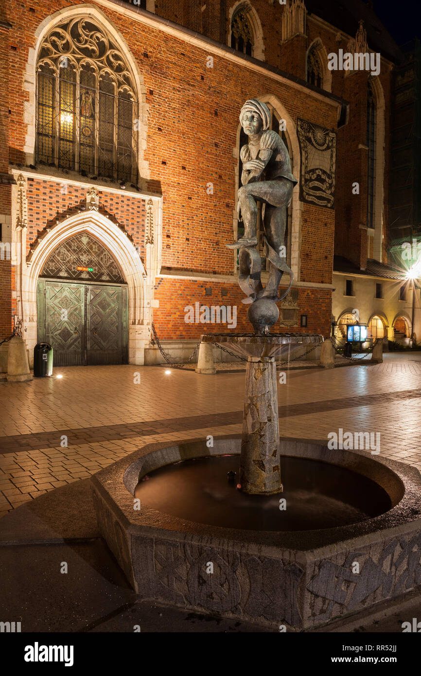 Poland, city of Krakow, Student statue at night, Zak Fountain on Mariacki Square in Old Town, St. Mary's Basilica in the background. Stock Photo