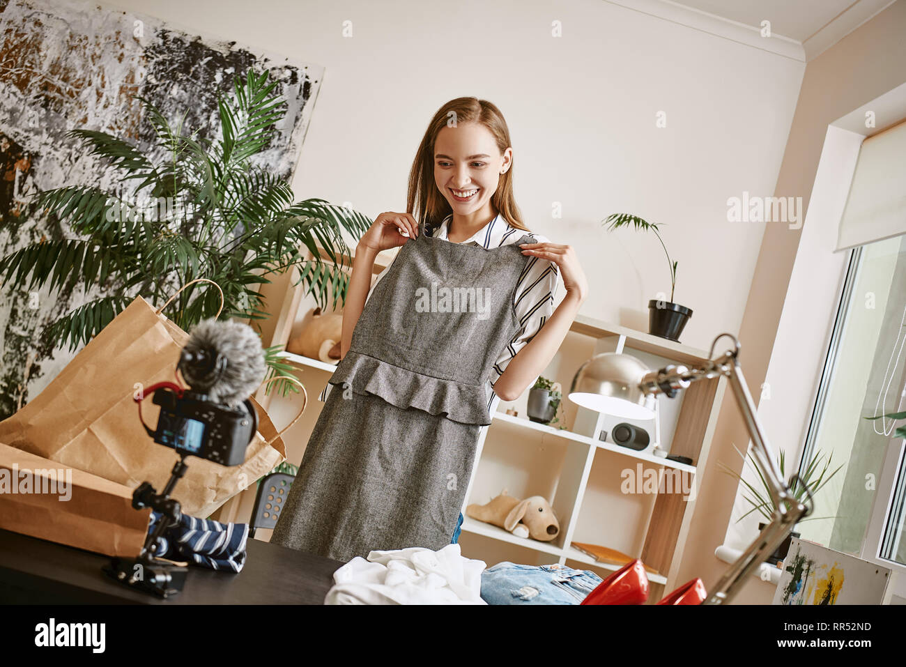 It suits me well, don't you think? Young female blogger recording video review about her new dress and smiling at camera. Fashion blog. Social media Stock Photo