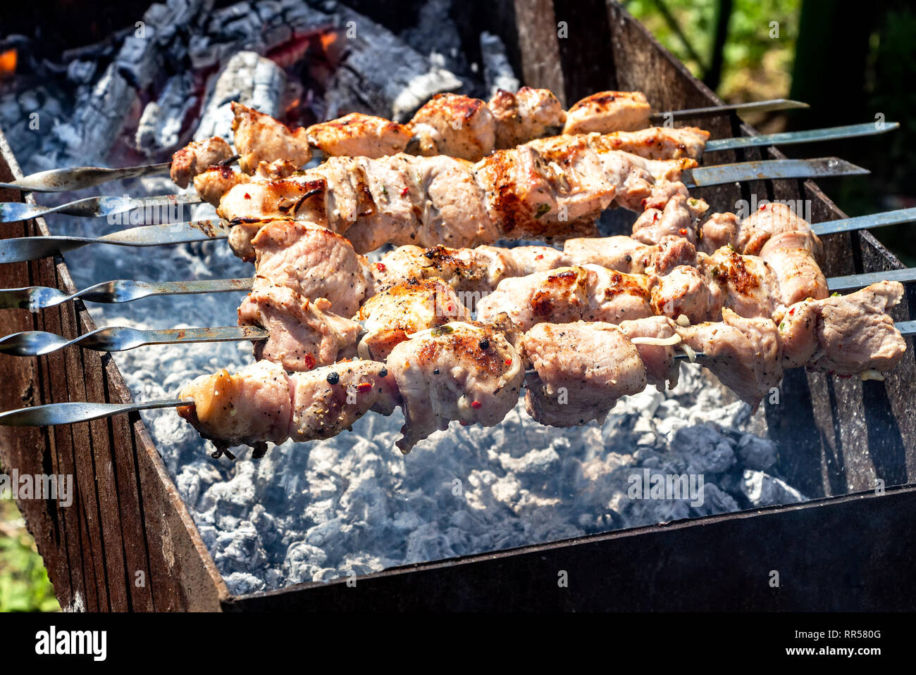 Grilled appetizing kebab cooking on metal skewers. Shashlik made of