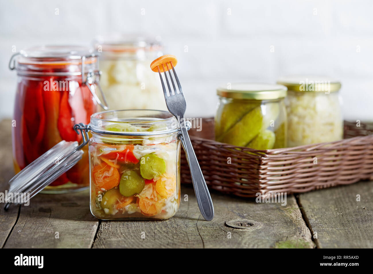 Autumn seasonal pickled vegetables in glass jars, on rustic wooden background. Stock Photo