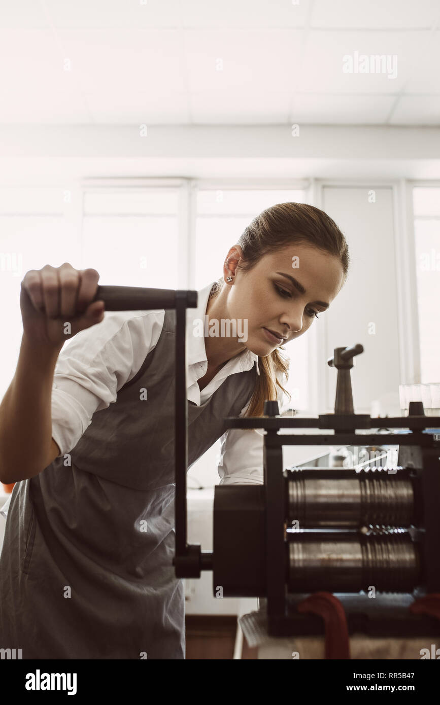 Manual method of work. Portrait of young female goldsmith crafting