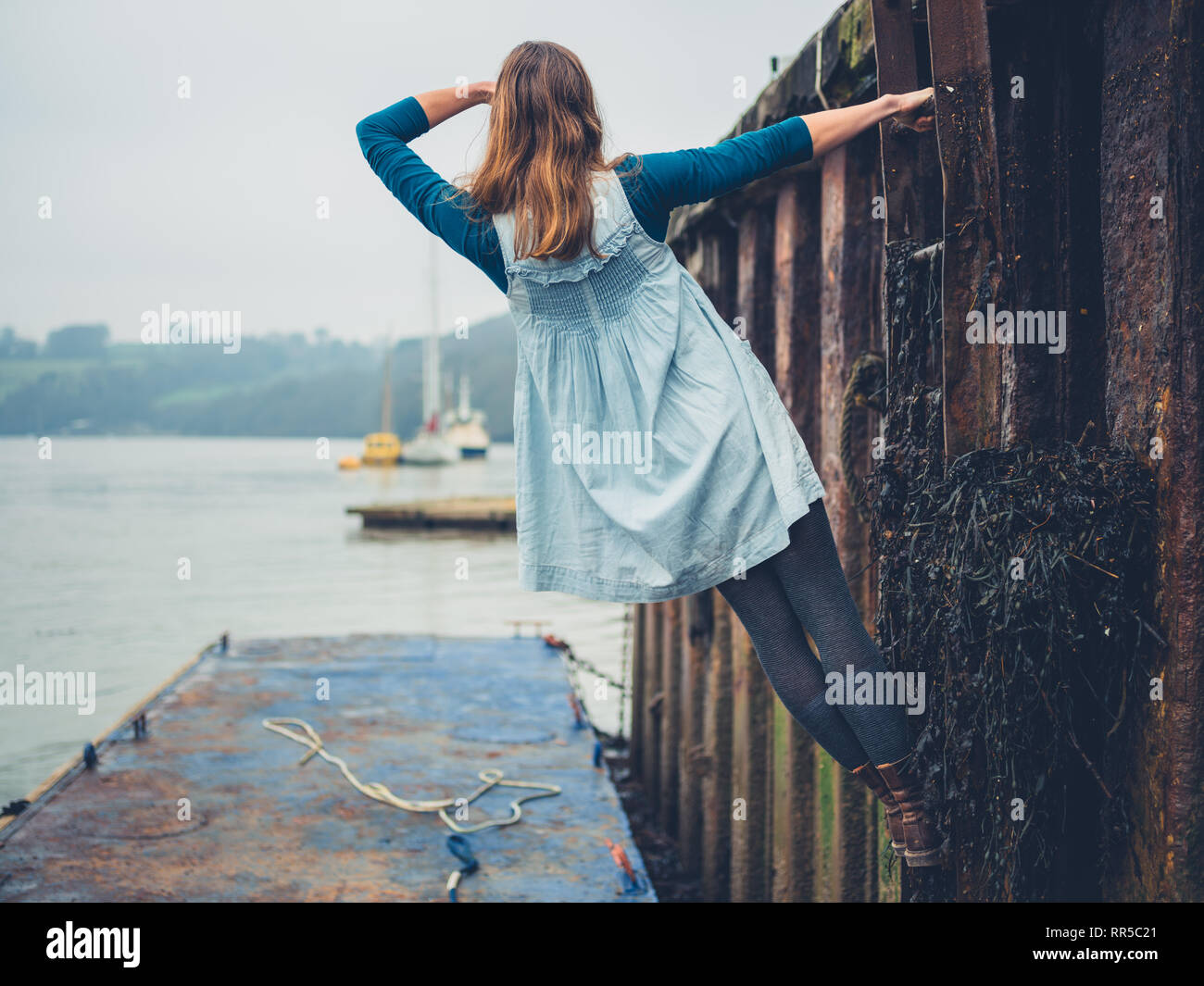 A young woman is hanging from a ladder in a shipyard Stock Photo - Alamy