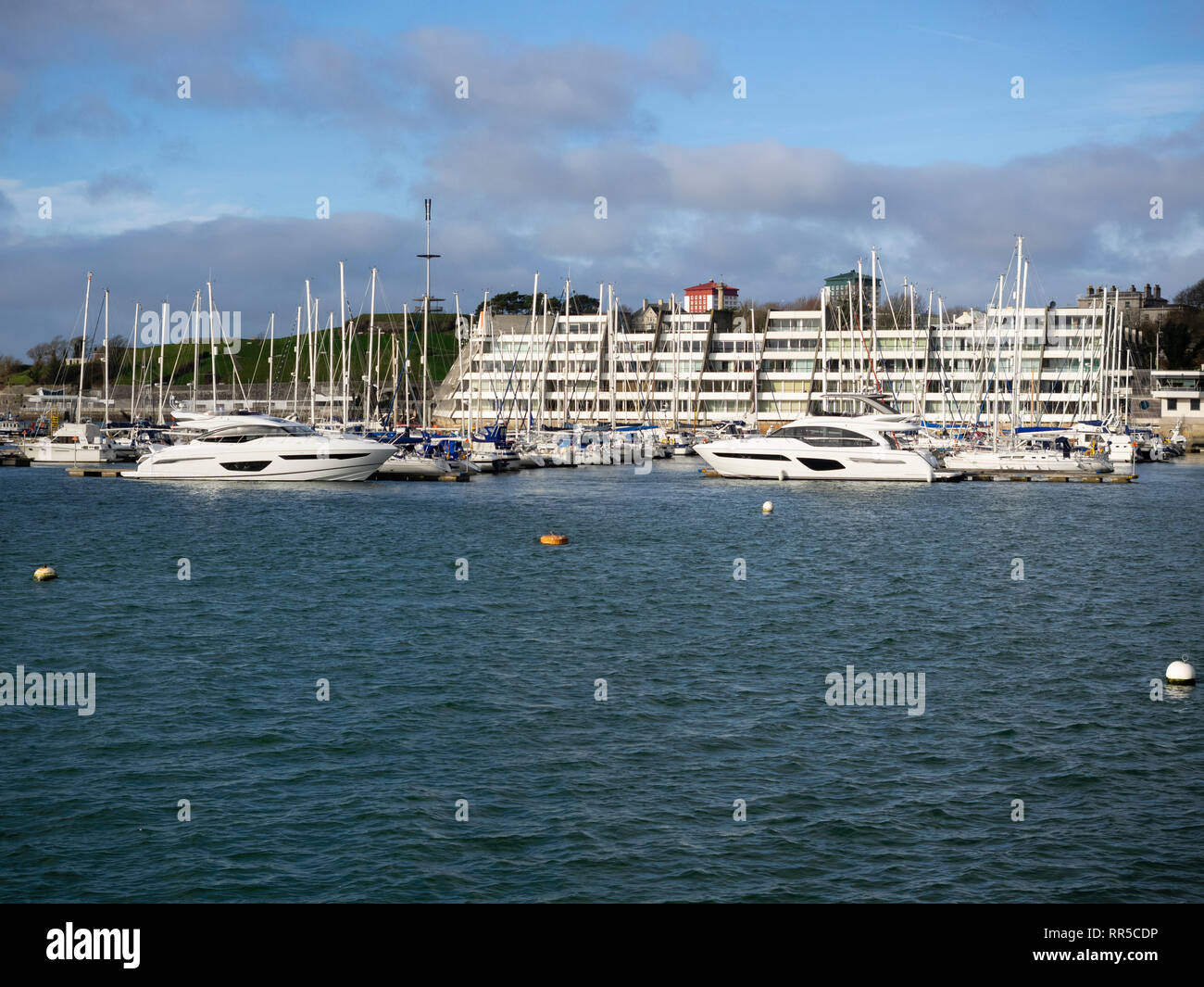 Sailing and motor yachts moored in front of the stepped apartments of