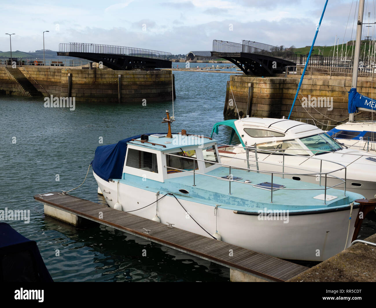 Motor boats moored in the harbour at the Royal William Yard in Plymouth, England. The harbour swing bridge is open Stock Photo