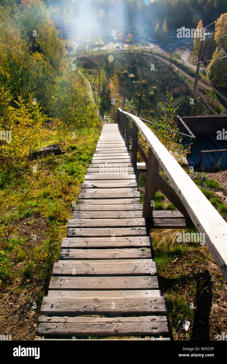 Long wood stairs down from top of bush-covered hill. Stock Photo