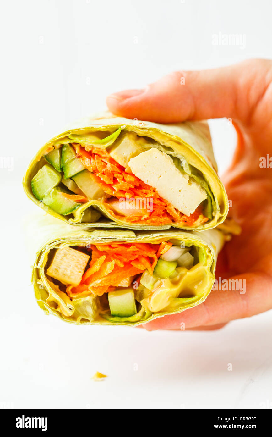 Vegan tofu wraps with cashew cheese sauce and vegetables in hand, white ... Vegan tofu wraps with cashew cheese sauce and vegetables in hand, white ...