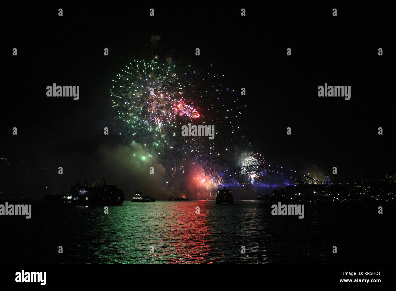 New Year's Eve fireworks in Sydney Harbor with bright reflections in the water. Stock Photo