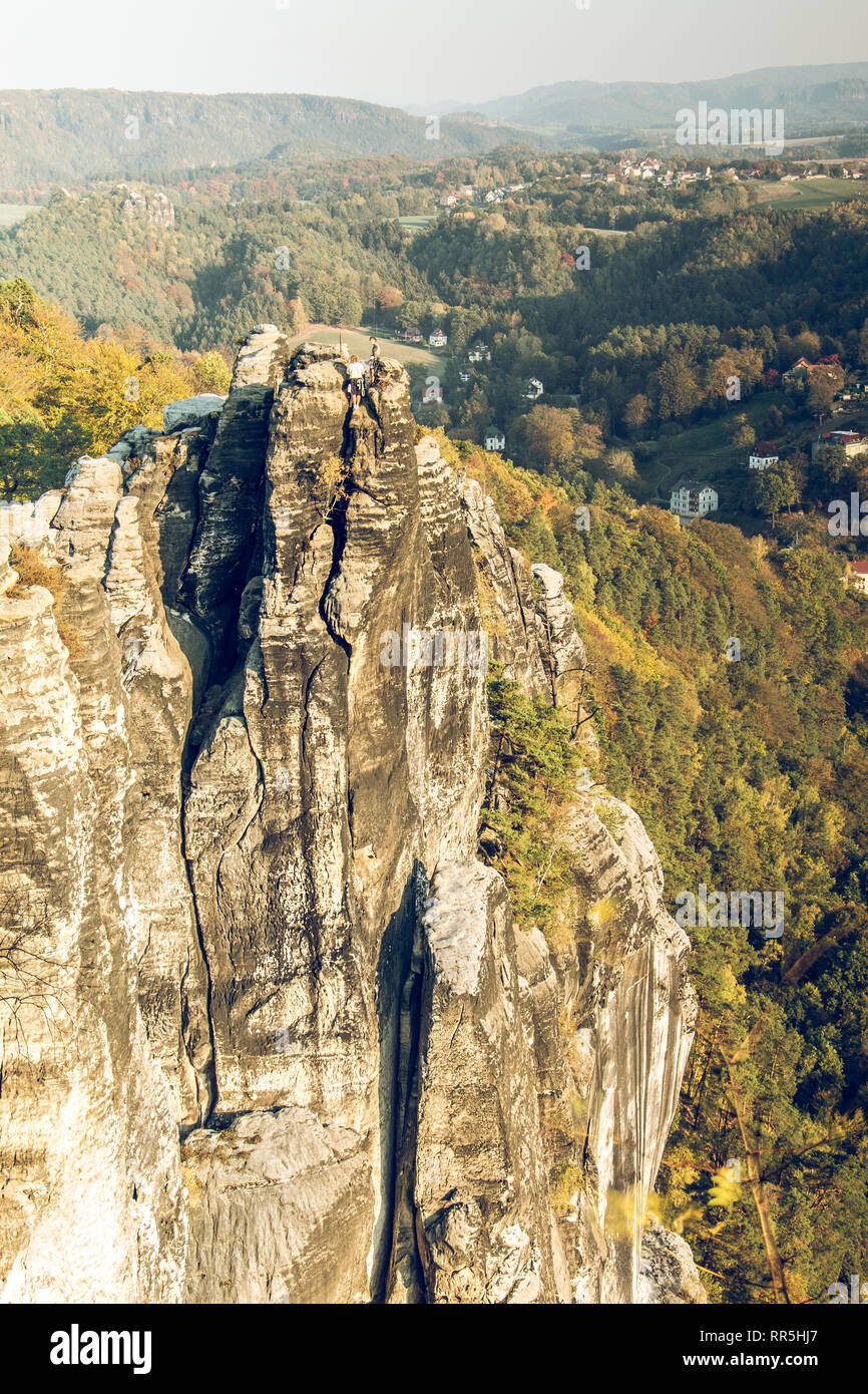 Rock formation in Saxon Switzerland. Rocks from the Elbe Sandstone Mountains tower with village and trees in autumn mood are in the background Stock Photo